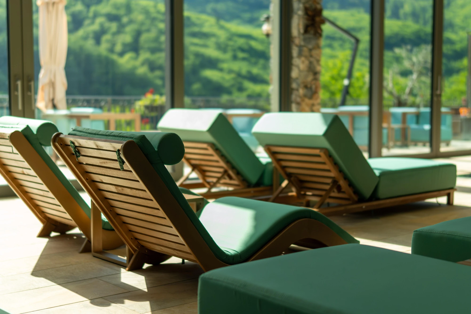 Șezlonguri în zona de spa, cu ferestre mari spre pădure